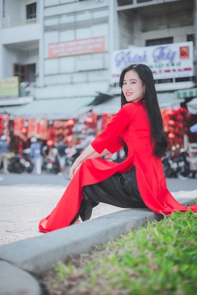 红色奥黛美女坐在花圃水泥板边上图片